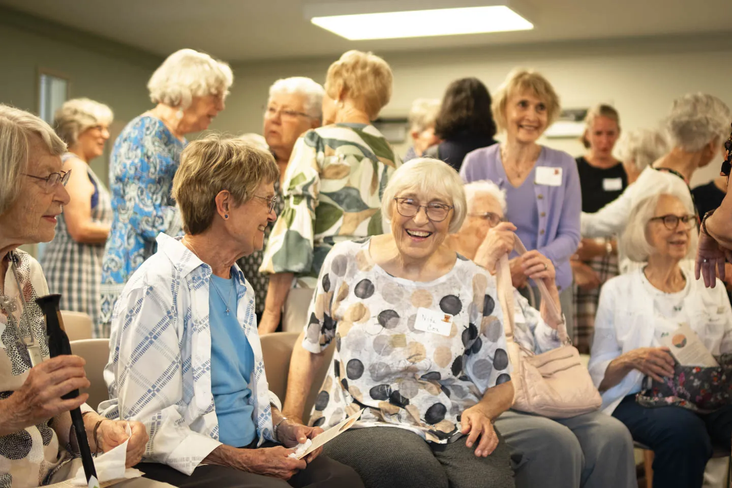 Members of the congregation seated and talking after a service, one of them laughing