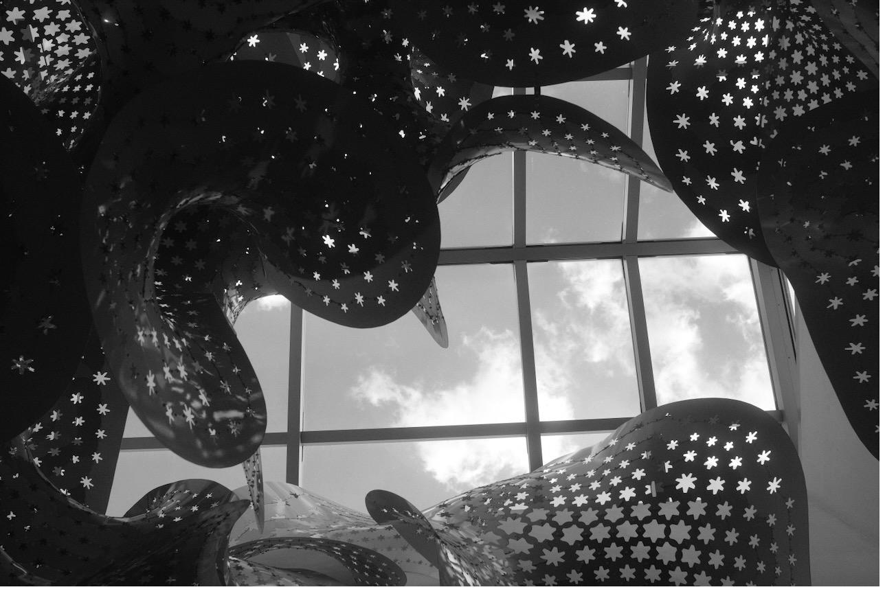 Perforated sculpture against a skylight, black and white