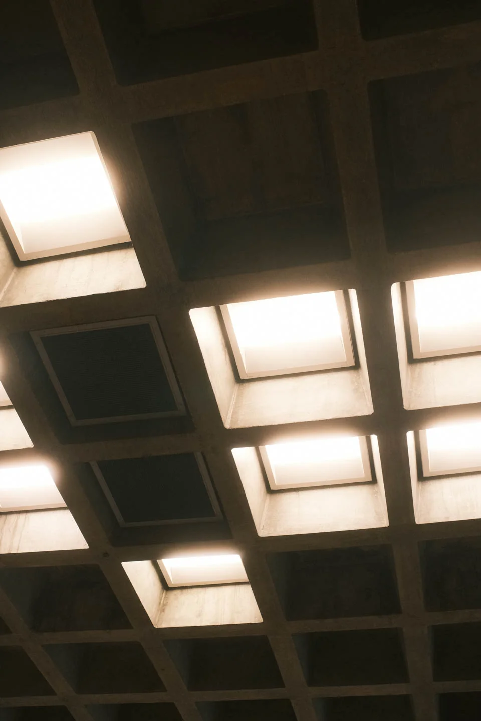 Warm light glowing through the coffered squares of a concrete ceiling