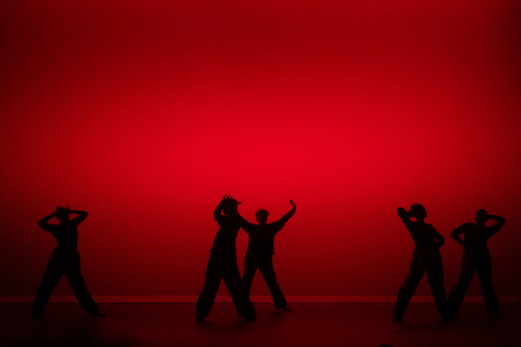 dancers silhouetted against a deep red stage wash