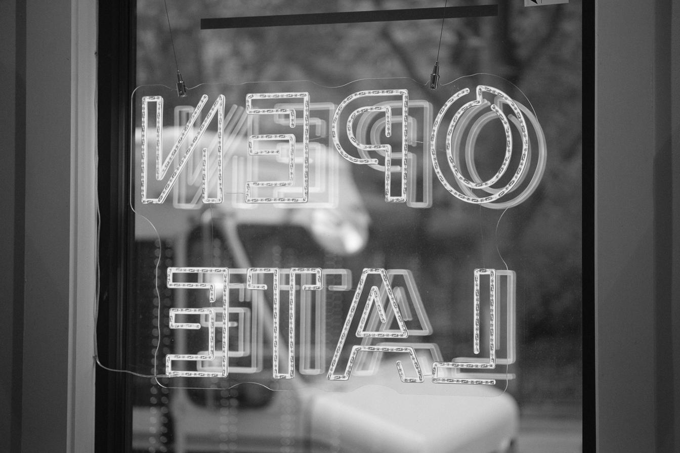 Neon 'open late' sign reversed in a storefront window